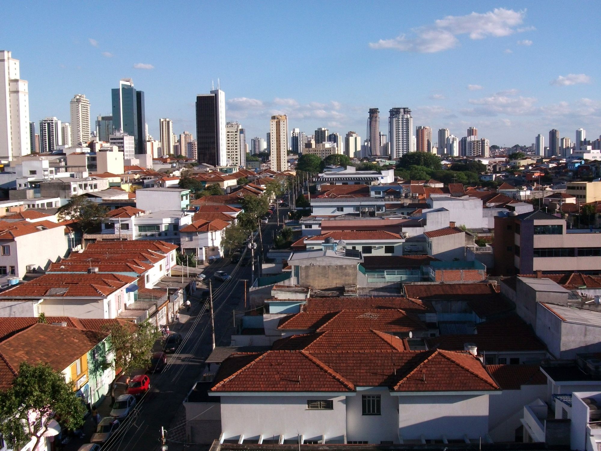Vista aérea da Zona Leste de São Paulo, com os telhados do bairro em primeiro plano e as torres do Tatuapé ao fundo